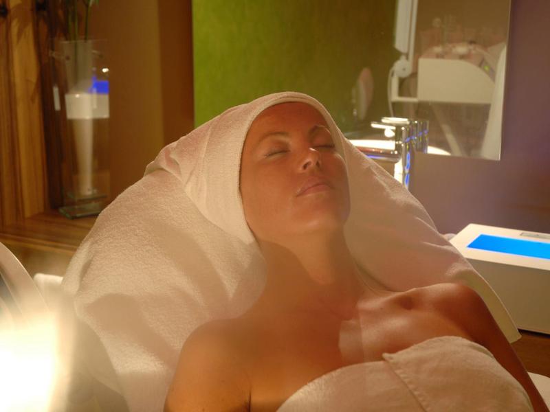 Kobieta leżąca owinięta białym ręcznikiem w relaksującej atmosferze spa.