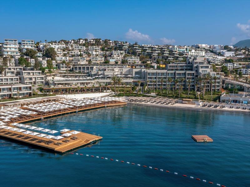 Panoramiczny widok luksusowego kurortu z basenami i drewnianymi tarasami nad morzem.