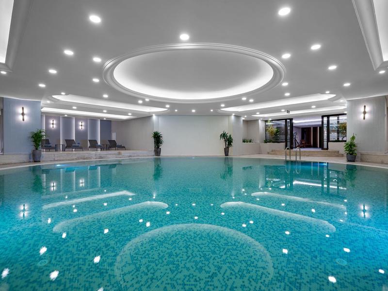 Nowoczesny basen kryty z okrągłym oświetleniem LED i wygodnymi miejscami do siedzenia.