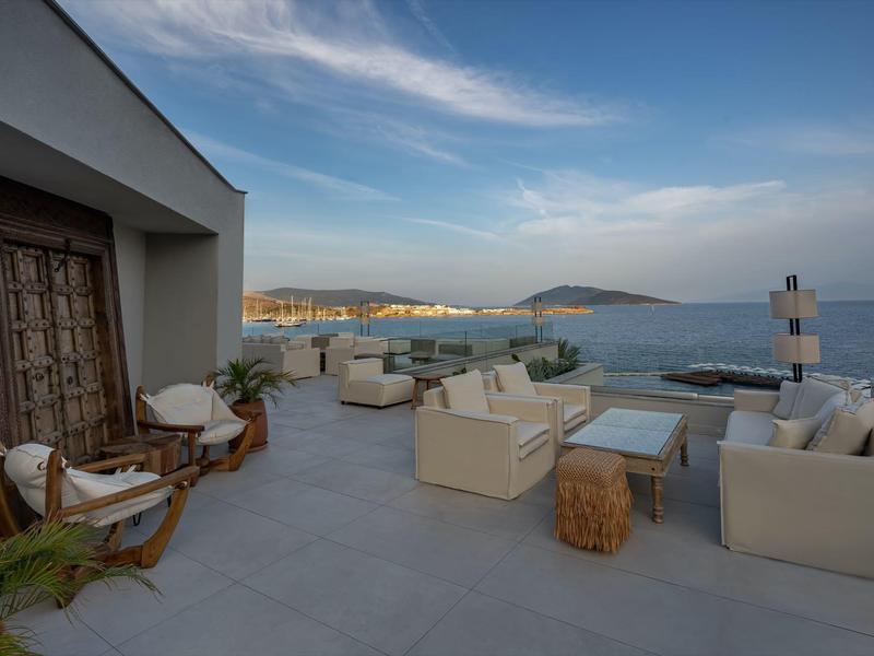 Przestronny taras z nowoczesnymi meblami z widokiem na morze i częściowo pochmurne niebo.