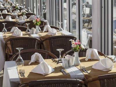 Restaurante elegante con mesas preparadas y vista al puerto a través de grandes ventanas.