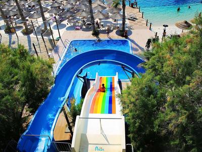 Vista de toboganes de agua coloridos con una piscina azul junto a una playa de arena