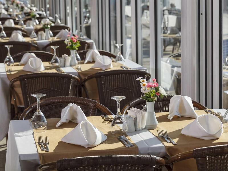 Restaurante elegante con mesas preparadas y vista al puerto a través de grandes ventanas.