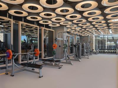 Moderne sportschool met gewichten en mensen die trainen in een hotel.