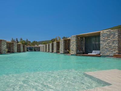 Modern hotelzwembad met ondiep, helder water en stenen gebouwen op de achtergrond onder een heldere lucht