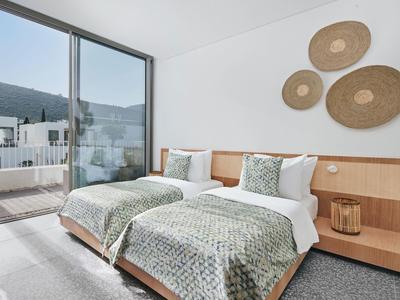 Bright twin room with two beds, modern wood decor, and balcony access with mountain view.