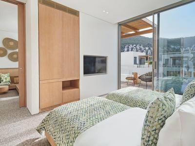 Modern bedroom with twin beds, large windows, and terrace view of mountains.