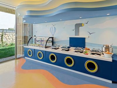 Colorful buffet with sea-themed circular windows in a bright dining area.