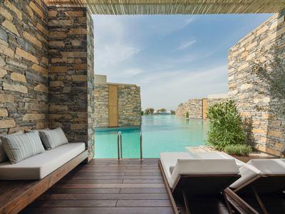 Modern terrace with pool and ocean view, surrounded by stone walls.