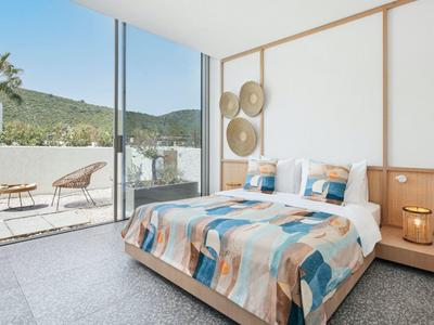 Bright bedroom with large bed, terrace doors, and outdoor seating area with mountain view.