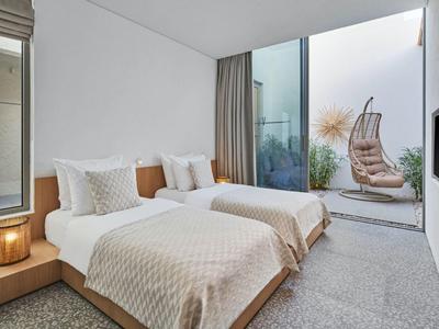 Modern hotel room with two single beds and view of terrace with hanging chair.