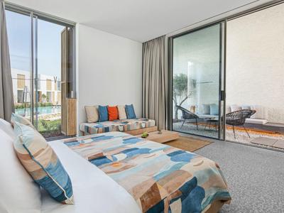 Modern hotel room with seating area and terrace access overlooking the city.