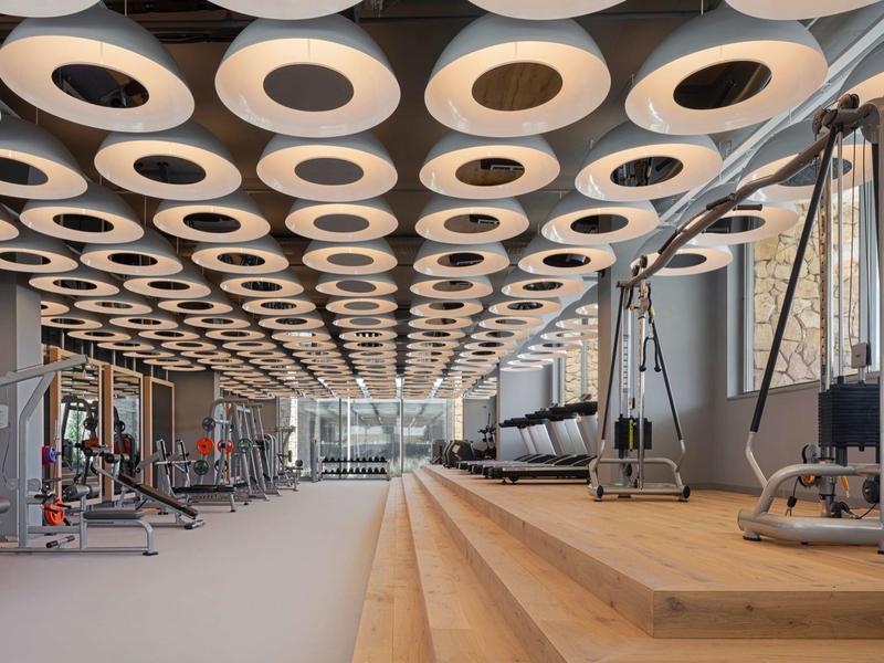 Modern gym with unique ceiling lights and various workout equipment.