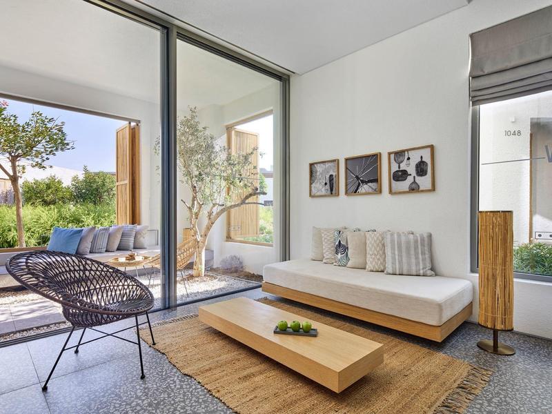 Modern living area with sofa, wooden coffee table, chairs, and access to terrace with garden view.