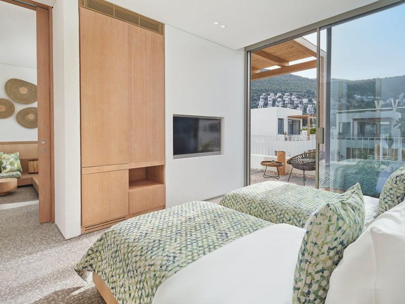 Modern bedroom with twin beds, large windows, and terrace view of mountains.