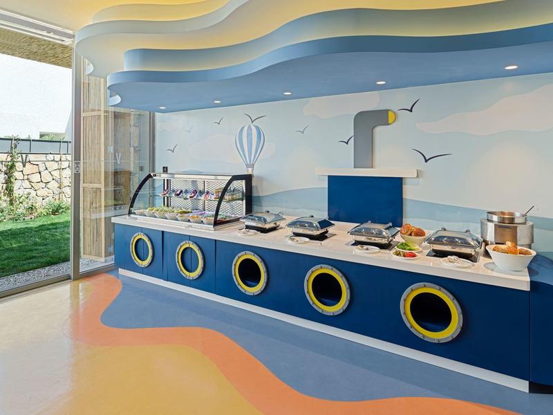 Colorful buffet with sea-themed circular windows in a bright dining area.