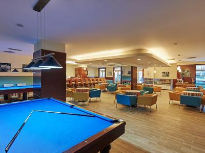 Lounge s modrým kulečníkovým stolem, křesly a bufetem v hotelu