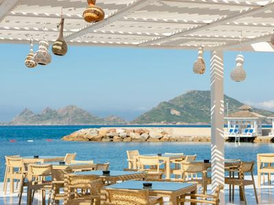 Open restaurant seating area with sea and mountains view in the background