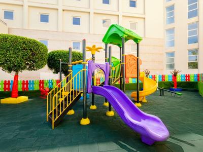 Colorful playground with slides and climbing structures in a secure courtyard.