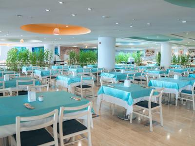 Large modern dining room with blue tablecloths and white chairs.