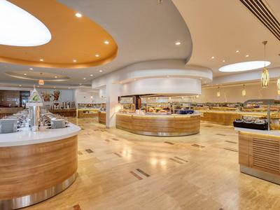 Bright buffet area with round wooden counters and indirect ceiling lighting.