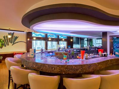 Moderne Hotelbar mit geschwungenem Tresen, bequemen Stühlen und stimmungsvoller Beleuchtung.