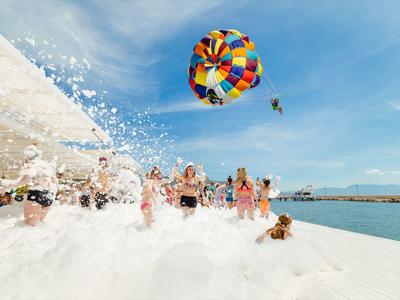 Lidé si užívají vodní sporty s barevným parasailingem nad mořem za slunečného dne.