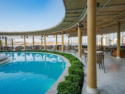 Round hotel pool under a large canopy with chairs and tables nearby.