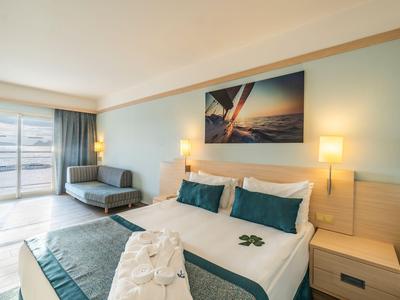 Modern eingerichtetes Hotelzimmer mit großem Bett, Balkon und Meerblick.
