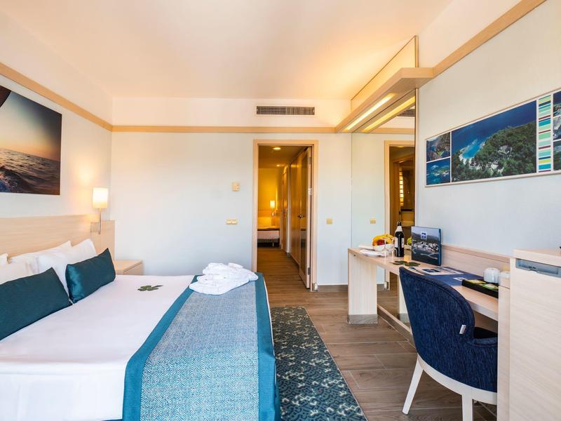 Modern hotel room with double bed, desk, and seating area, bright and inviting.