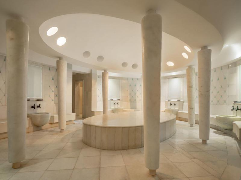A bright spa area with marble columns and a round table in the center.