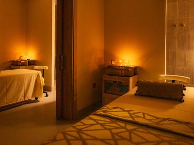 Salle de spa confortable avec deux tables de massage et éclairage tamisé.