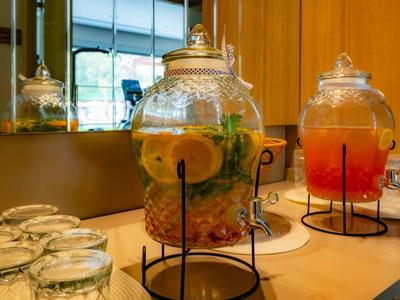 Deux grands distributeurs en verre avec des boissons sont posés sur un comptoir à côté de plusieurs verres.