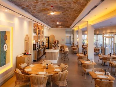 Restaurant d'hôtel lumineux et accueillant avec chaises en bois et rotin, éclairage chaleureux et plafond décoratif.