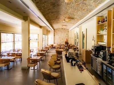 Restaurant moderne et lumineux avec grandes tables, bar, grandes fenêtres et plafond élégant.