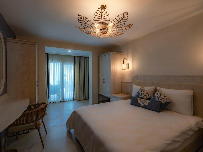 Chambre d'hôtel moderne avec lit double, bureau, balcon et éclairage doux.