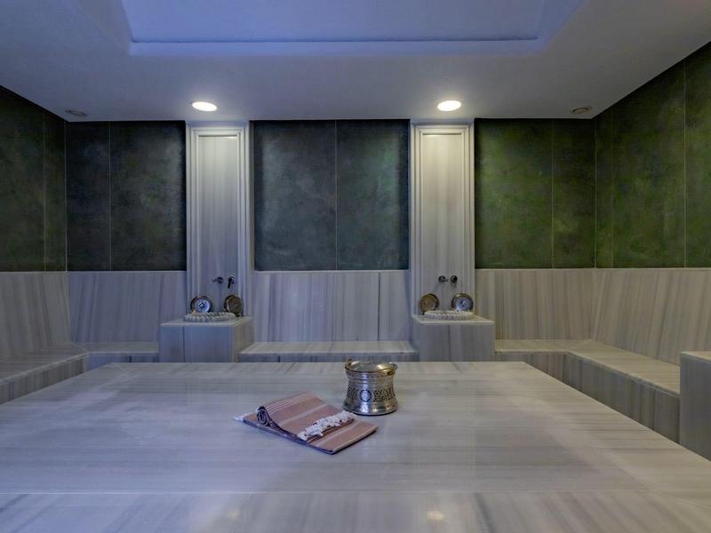 Salle de vapeur moderne et calme avec murs en bois et sol minéral.