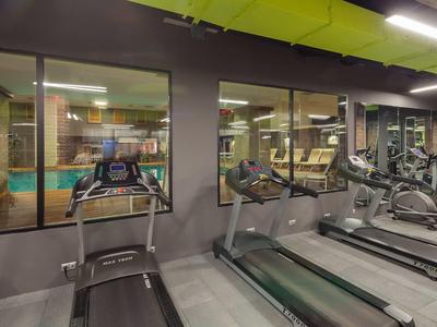 Salle de sport moderne avec tapis de course et vue sur le court de tennis.