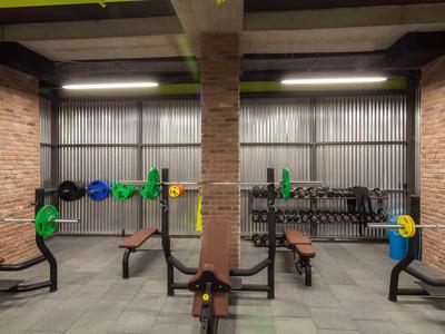 Salle de sport moderne avec bancs de musculation et poids colorés accrochés au mur.