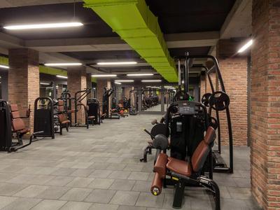 Grande salle de sport avec diverses machines de musculation et équipements modernes.