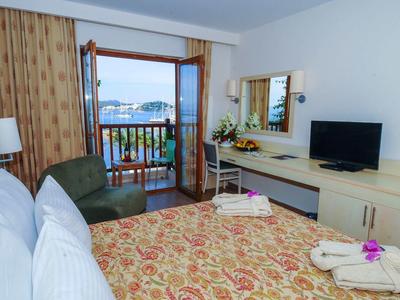 Chambre d'hôtel avec balcon et vue sur la mer, équipée d'un lit, d'un canapé, d'une télévision et d'un bureau.