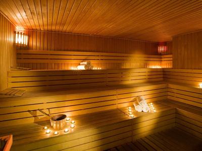 Holzsauna mit mehrstufigen Bänken, warmem Licht und Teelichtern für gemütliche Atmosphäre.