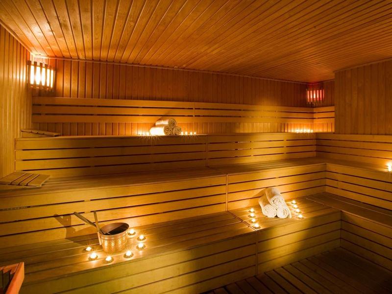 Holzsauna mit mehrstufigen Bänken, warmem Licht und Teelichtern für gemütliche Atmosphäre.