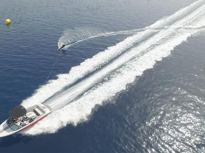 Un motoscafo veloce traina uno sciatore nautico su acqua calma.