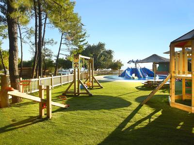 Children's playground with swings, climbing frames, and grass under a clear blue sky