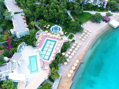 Aerial view of a resort with pools, sun loungers, and clear turquoise sea