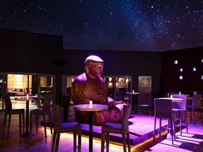Statua in un bar d'hotel elegante con cielo stellato e illuminazione moderna