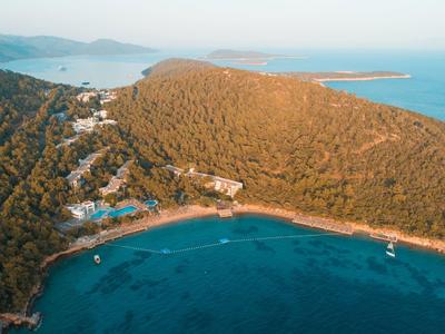 Aerial view of a bay with clear blue water surrounded by hills and green vegetation.