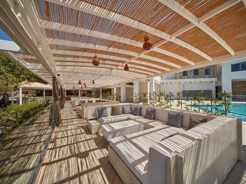 Lounge area with stylish seating and pool under a wooden and bamboo roof.
