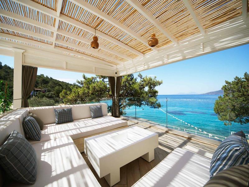 Covered terrace with cozy seating and sea view on the coastline.